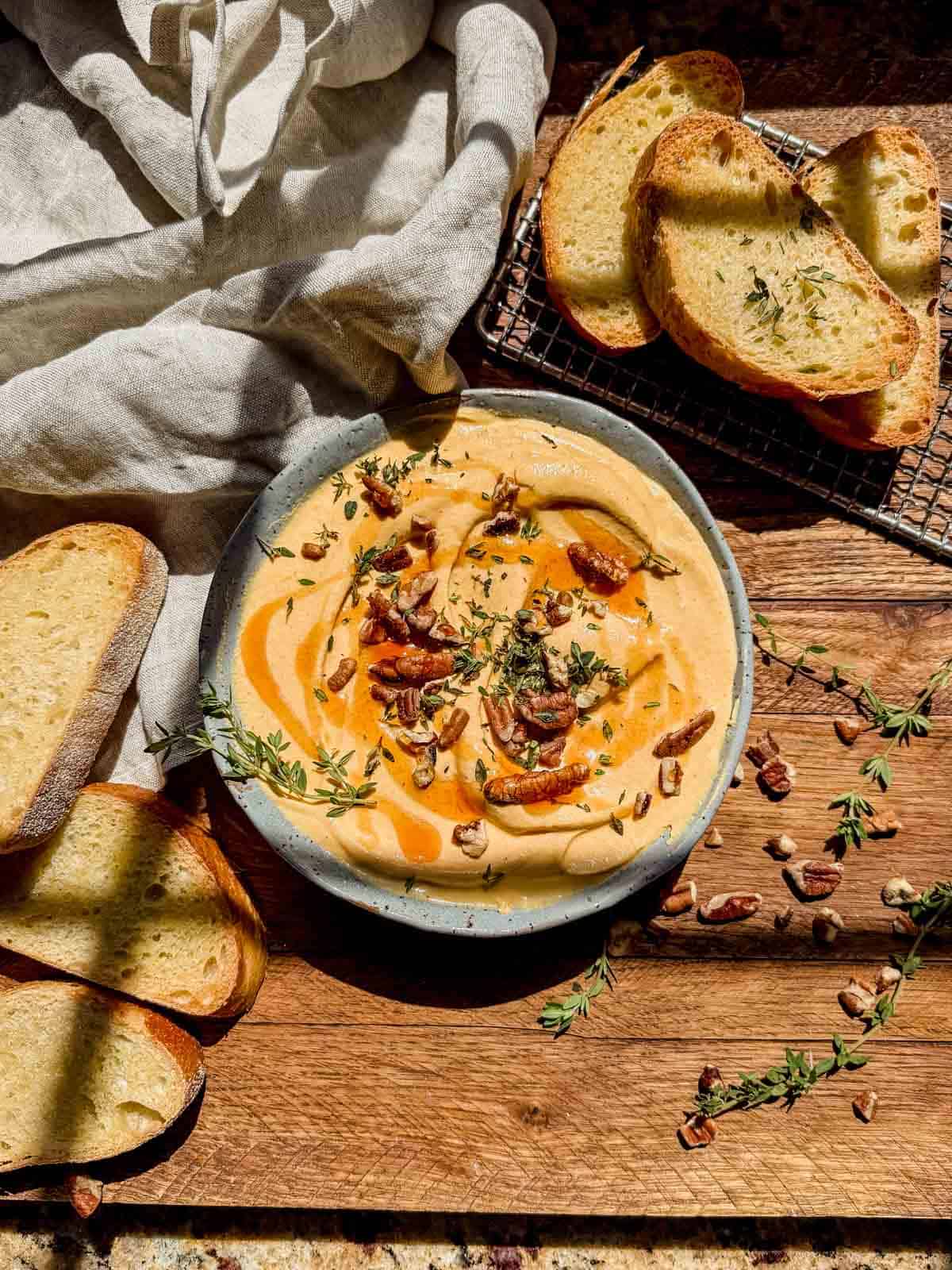 pumpkin whipped feta in a serving bowl topped with honey, feta, and pecans.
