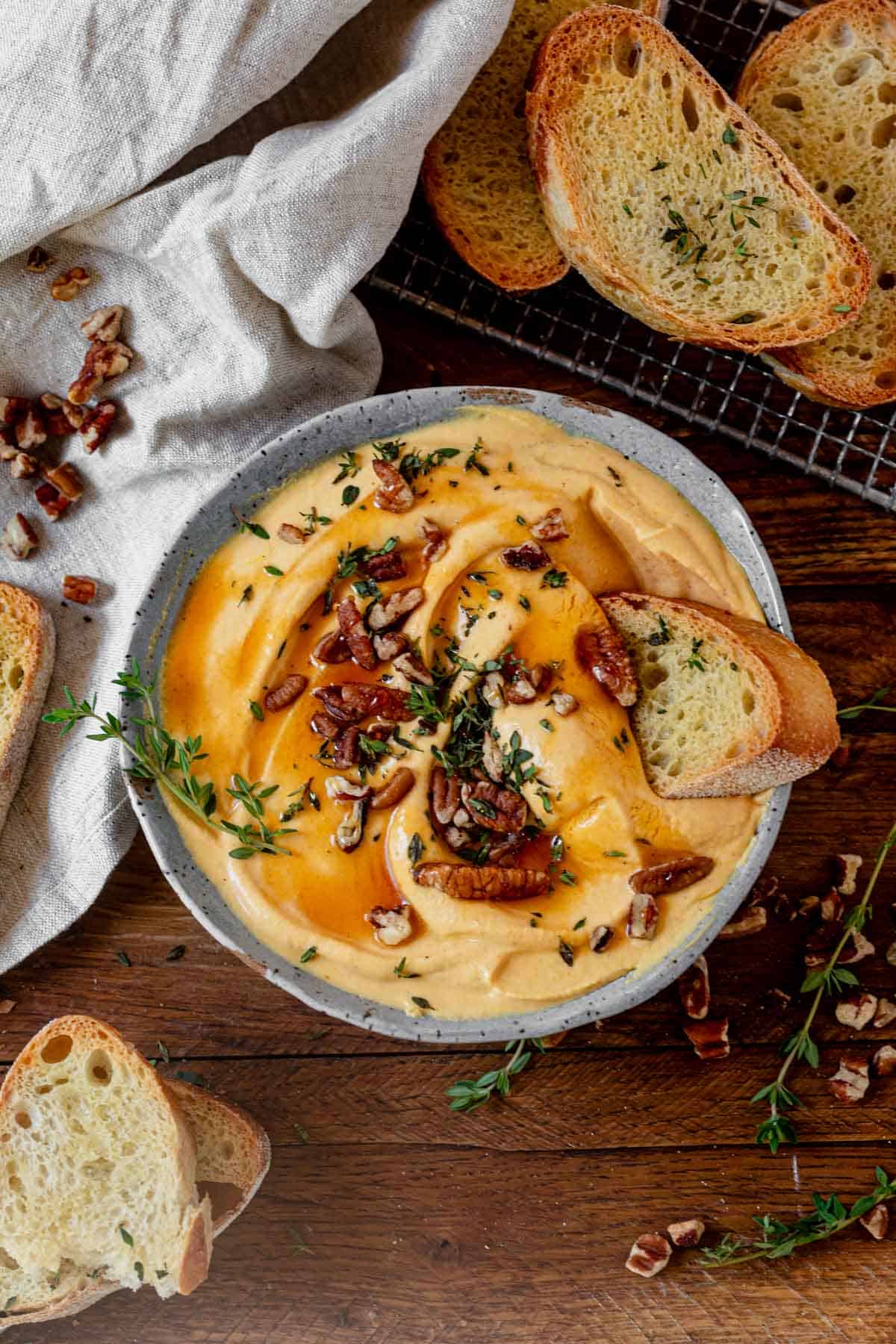 a bowl of pumpkin whipped feta on a serving tray with crusty bread.