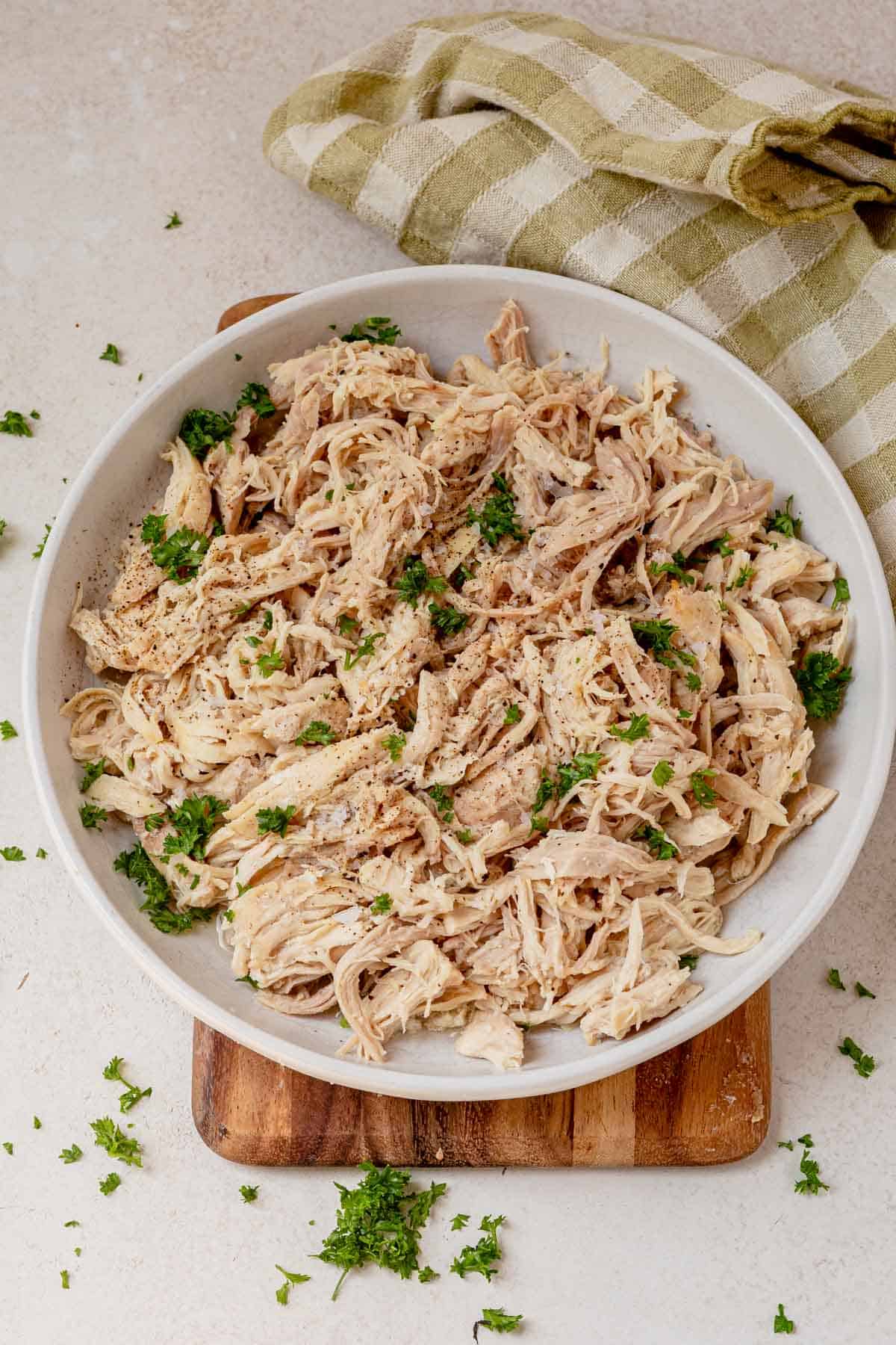 a bowl of slow cooker shredded chicken topped with parsley.