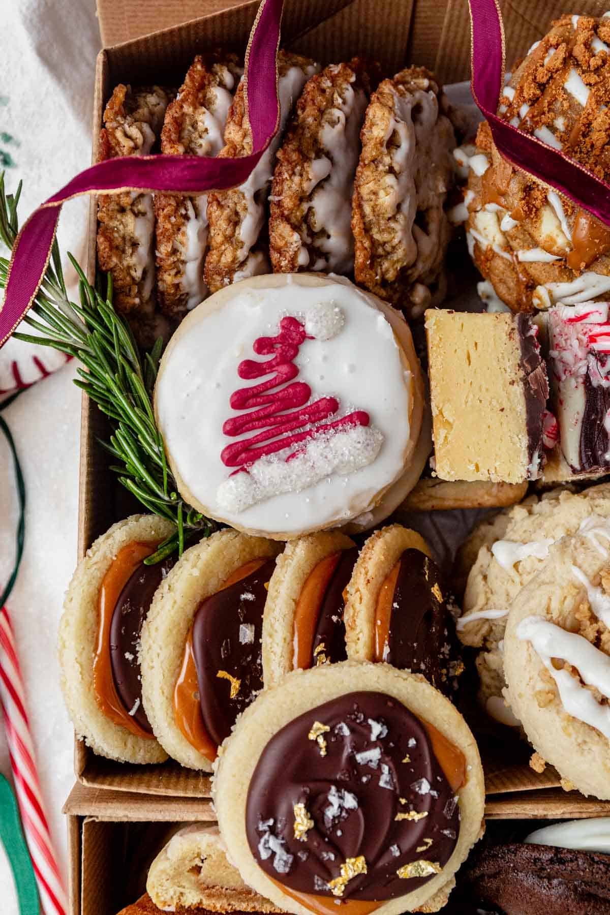 christmas cookies with santa hats in a cookie box with more holiday cookies.