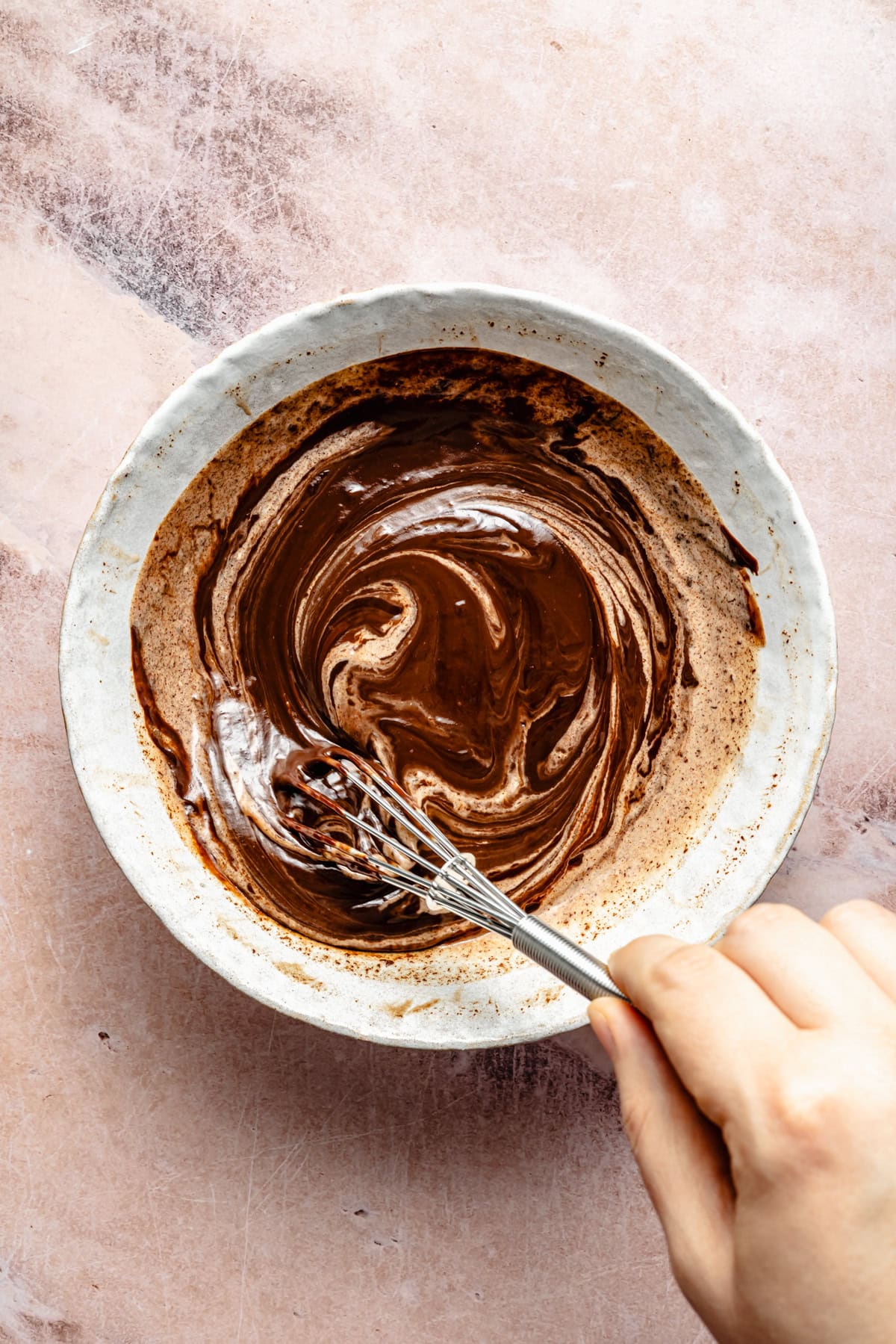 whisking chocolate ganache in a mixing bowl.