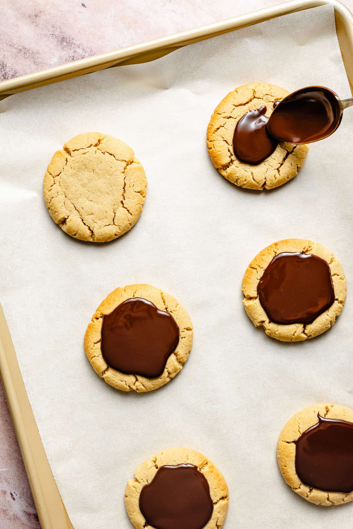 spreading chocolate ganache on top of homemade baked peanut butter cookies.
