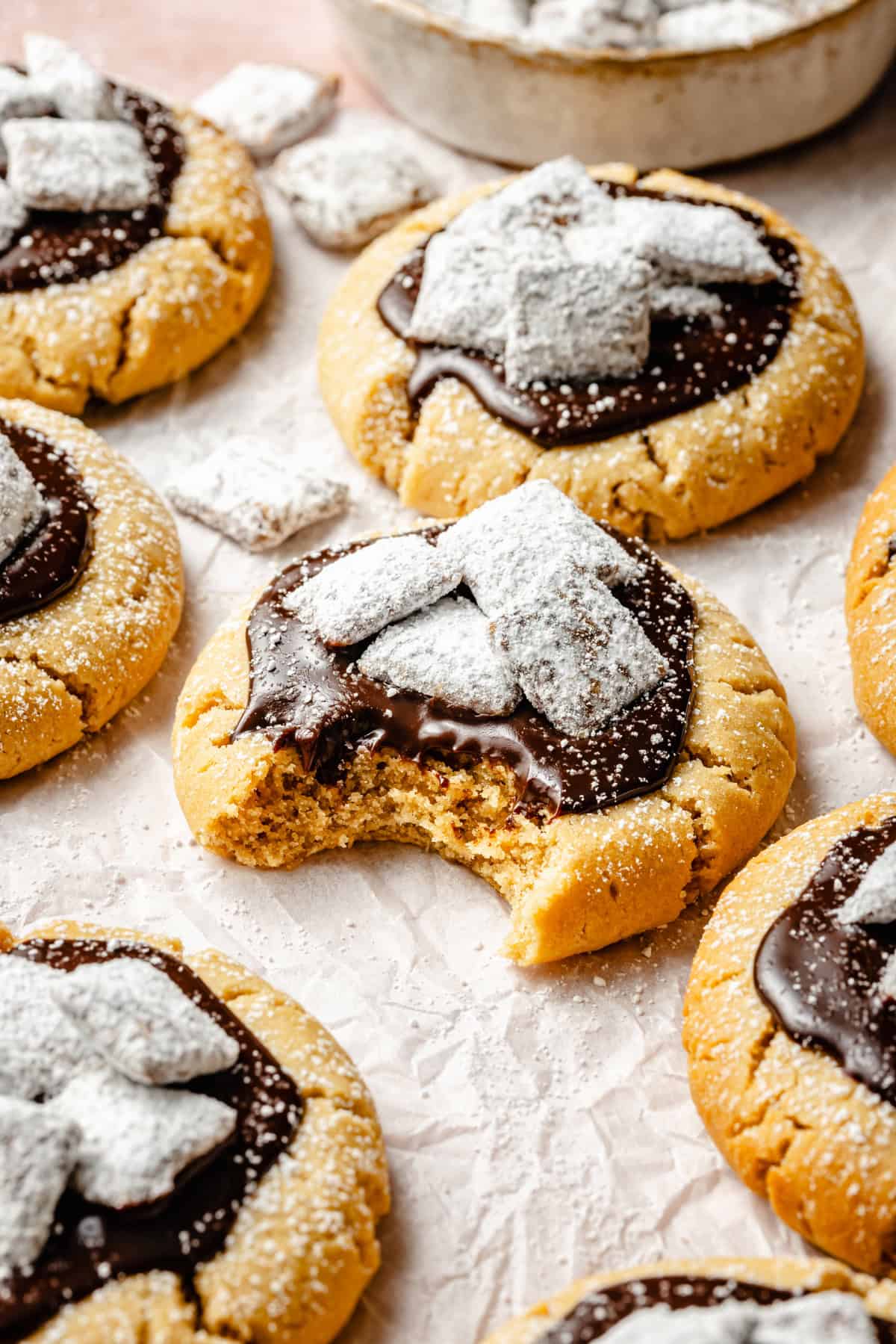 a bite taken out of a soft puppy chow peanut butter cookie topped with ganache and muddy buddys