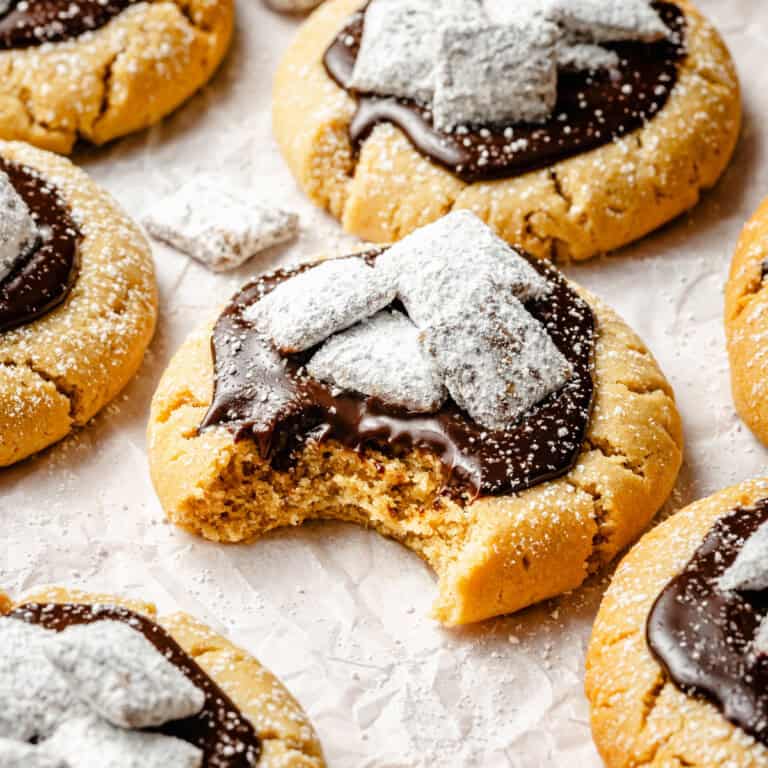 muddy buddy cookies on a piece of parchment paper with a bite missing from the center cookie.