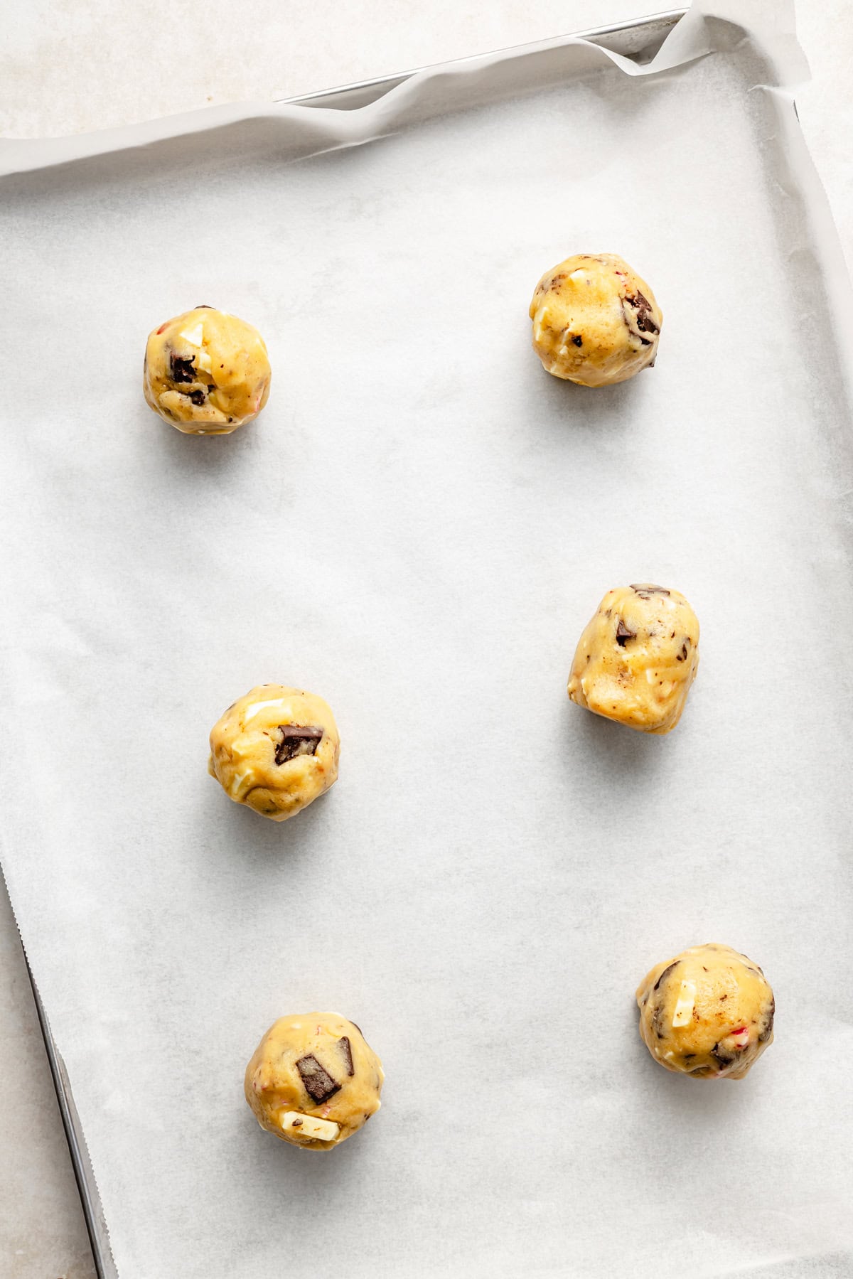 peppermint chocolate chip cookie dough balls on a baking sheet with parchment paper.