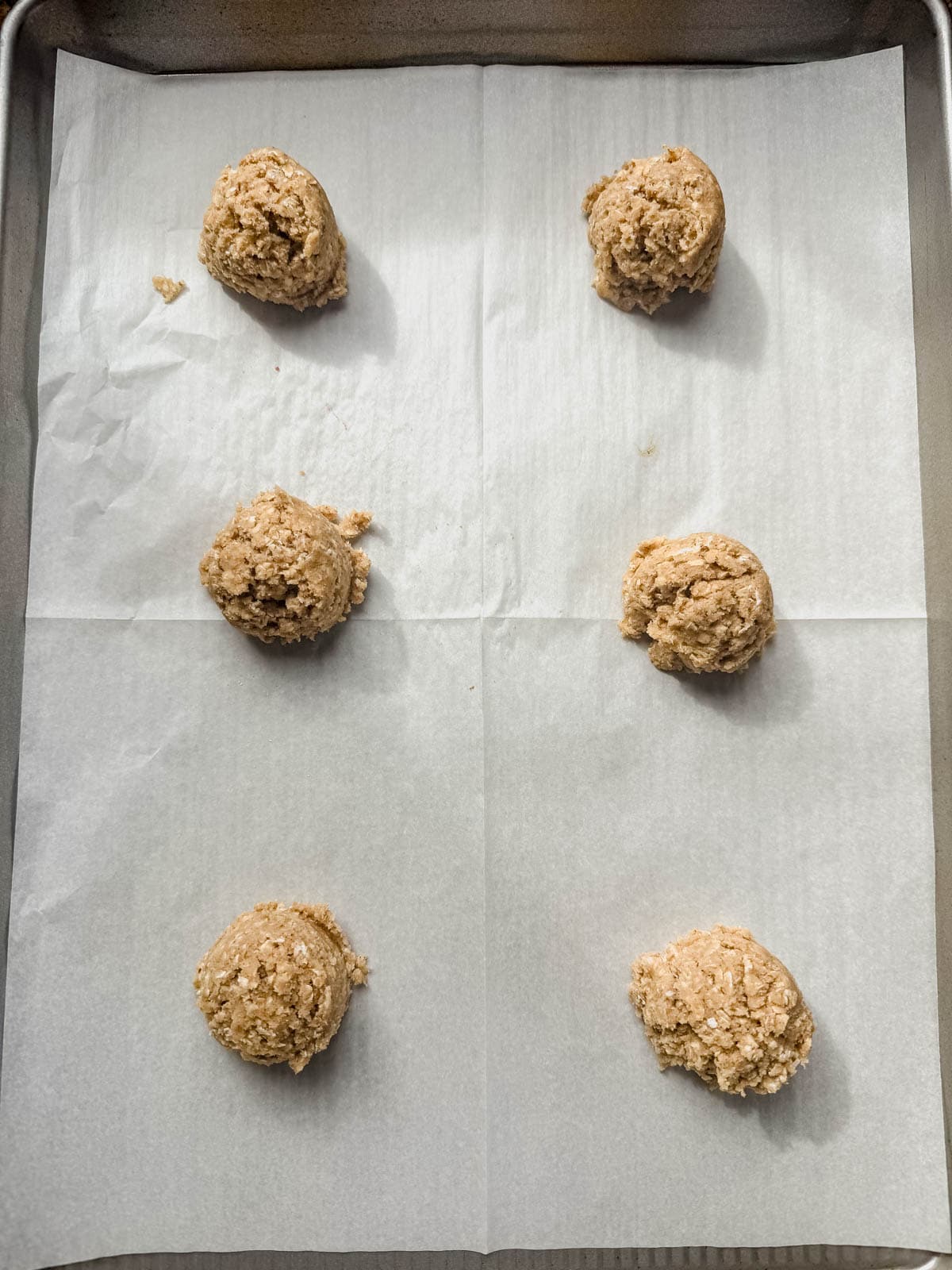 oatmeal cream pie cookie dough scooped into balls on parchment paper before baking.