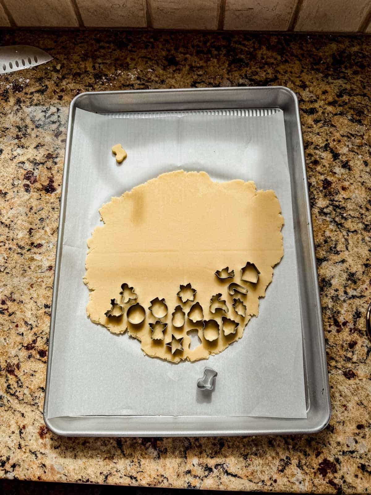 cutting mini christmas shapes out of sugar cookie dough.