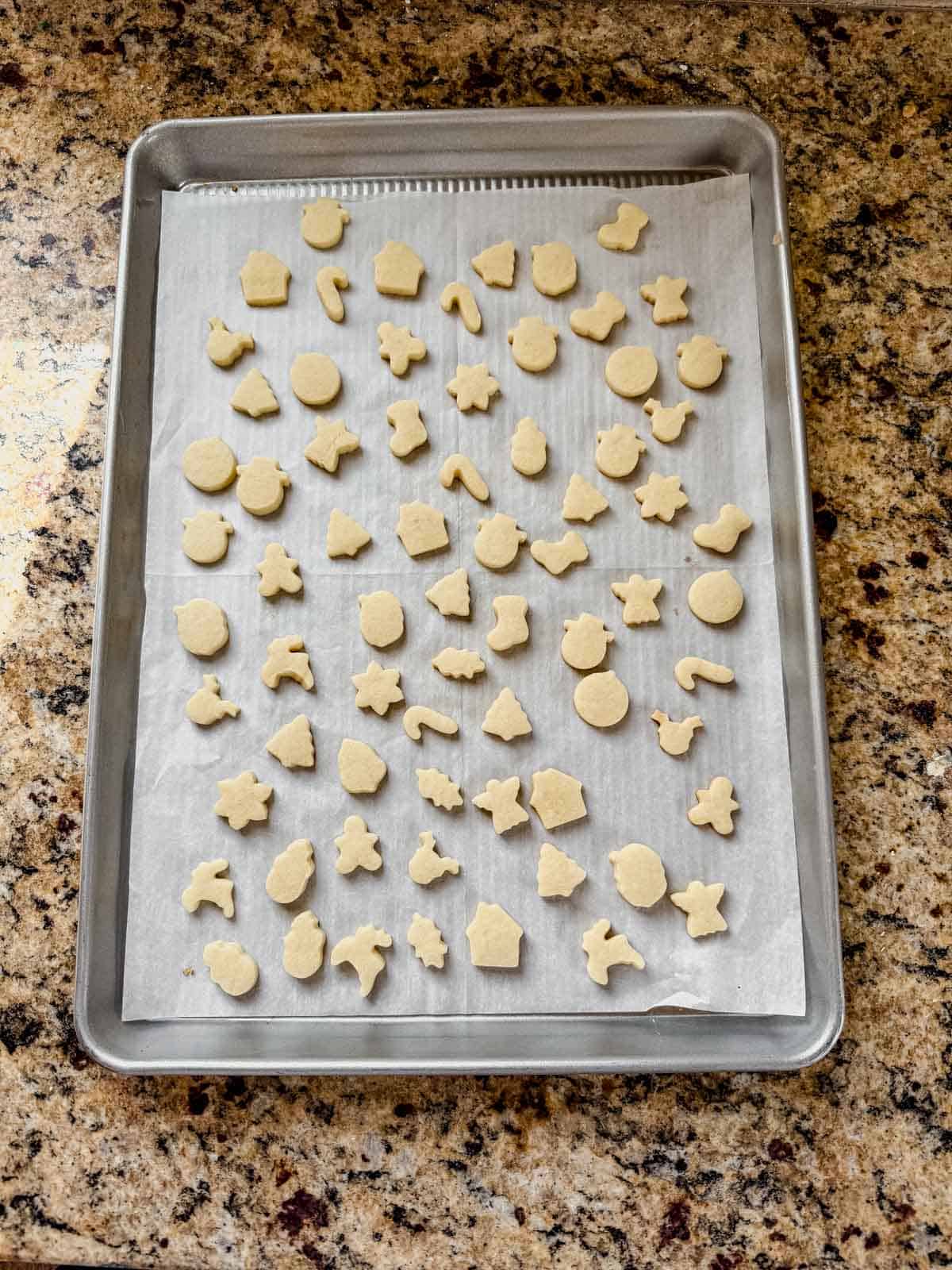 baked mini christmas cookies cooling on a baking sheet.
