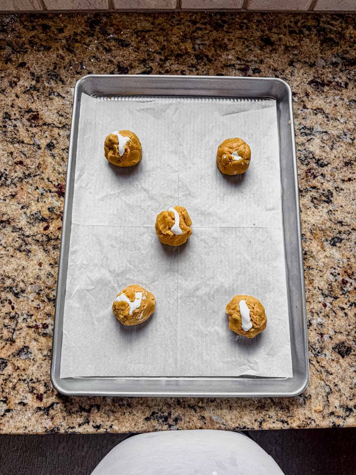 Two halves of the fluffernutter cookie dough pinched together at the seams but leaving some of the marshmallow showing. 