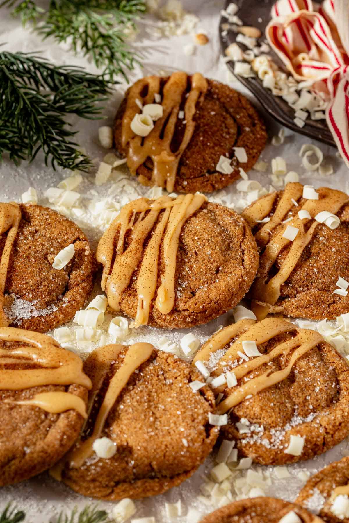 gingerbread latte cookies with brown butter glaze on a piece of parchment paper with a cup of coffee next to them.