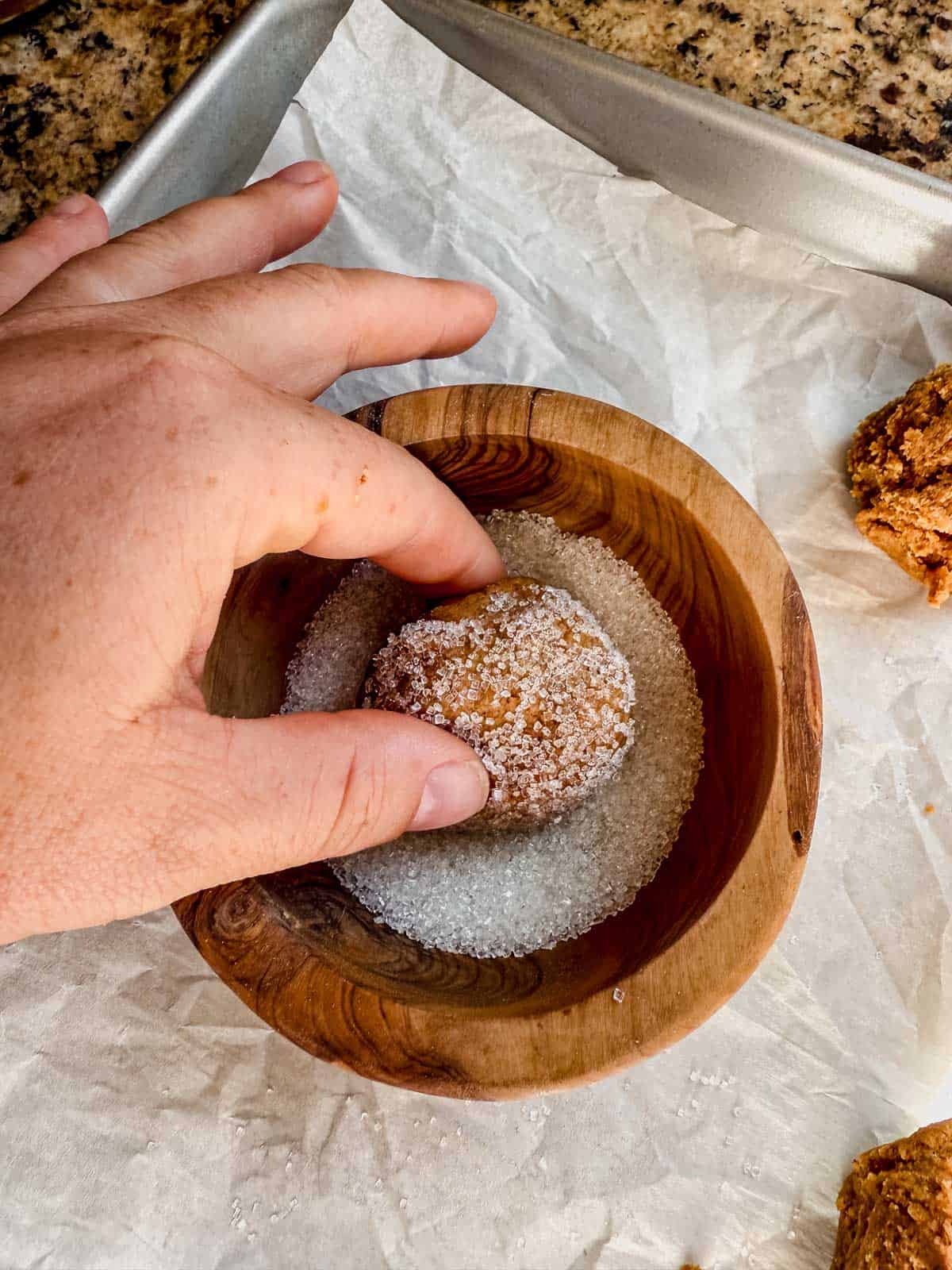 rolling gingerbread latte cookie dough ball in a bowl of sugar.
