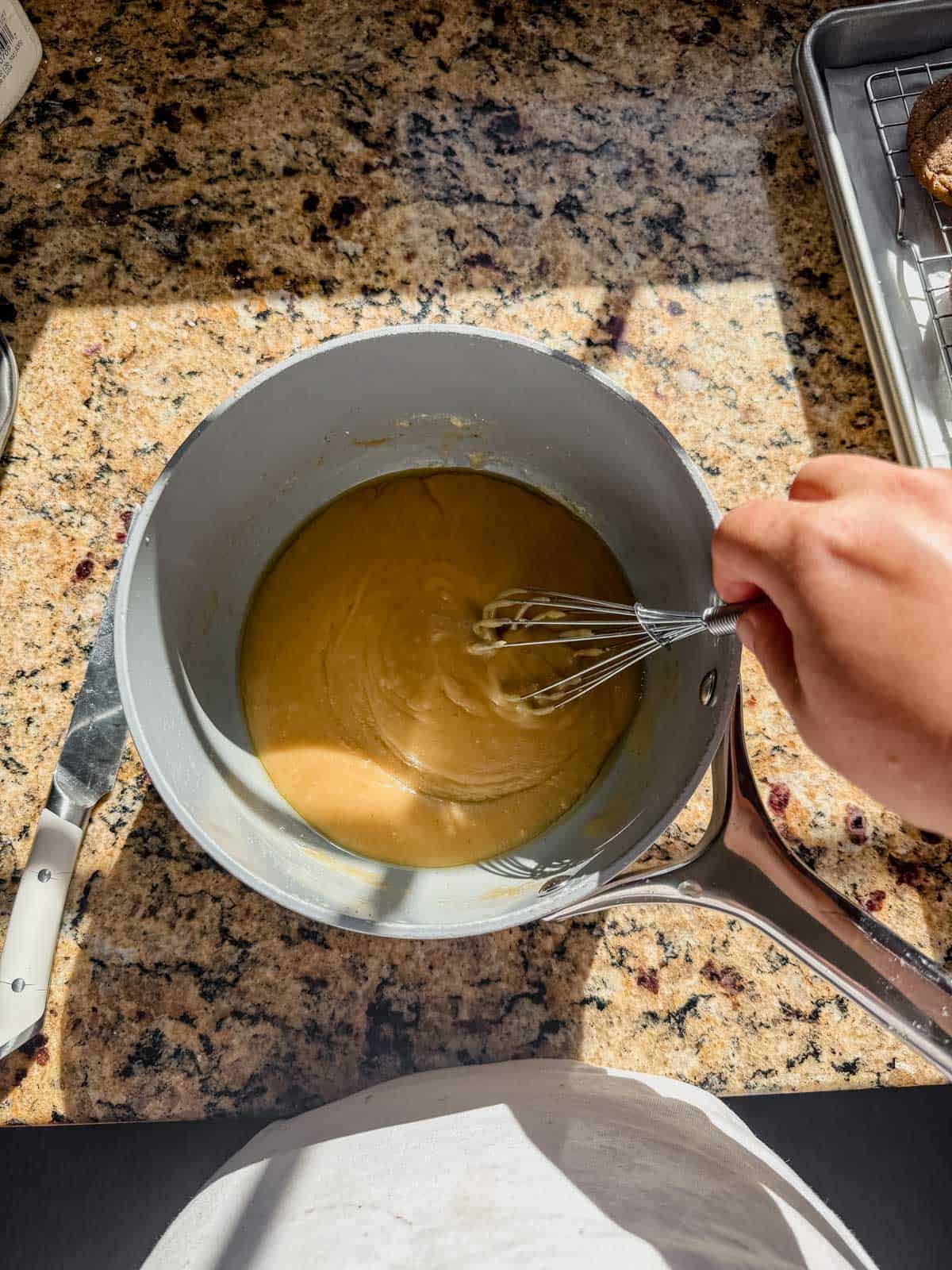 whisking a brown butter glaze in a saucepan.