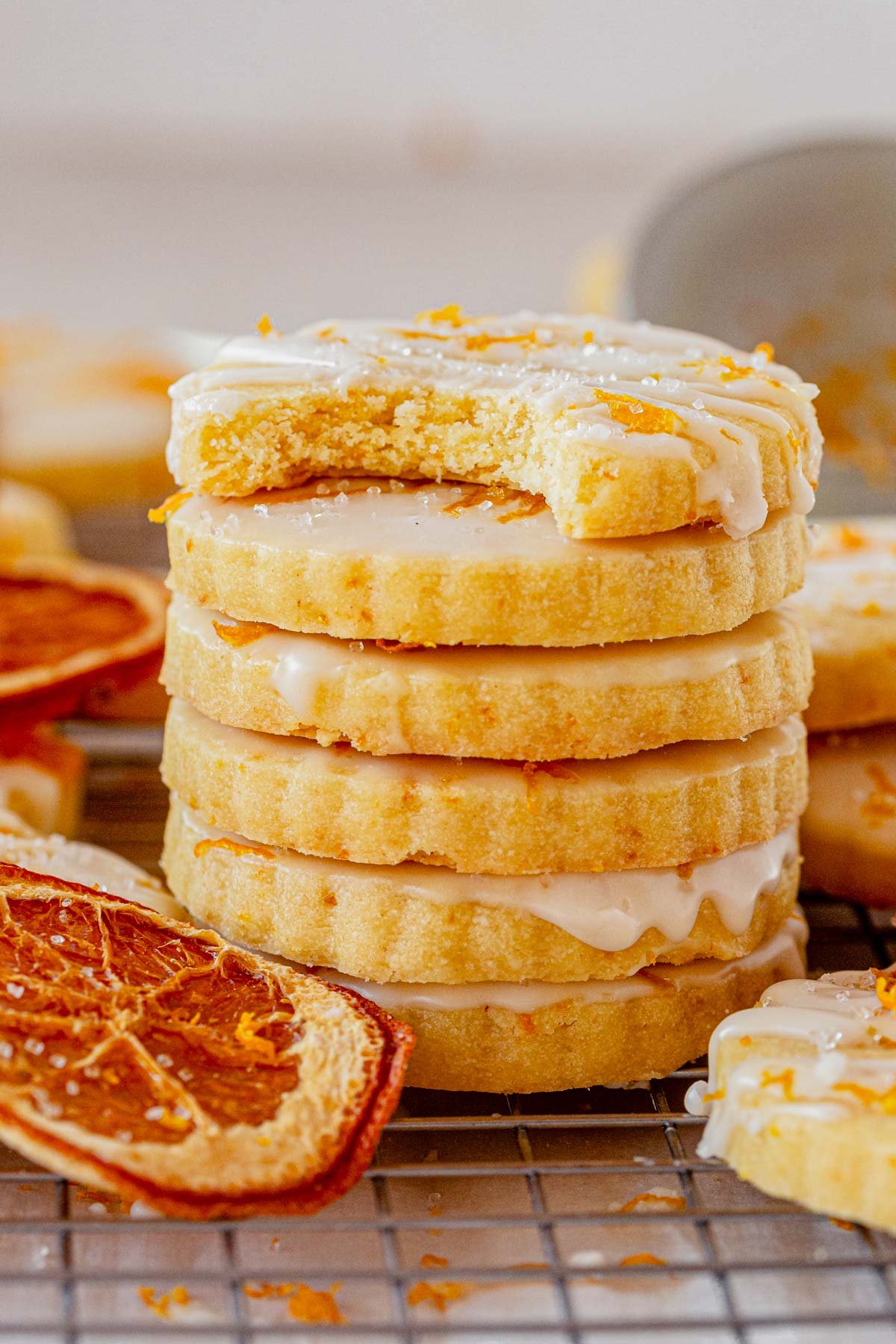 a stack of glazed orange shortbread cookies on a cooling rack.