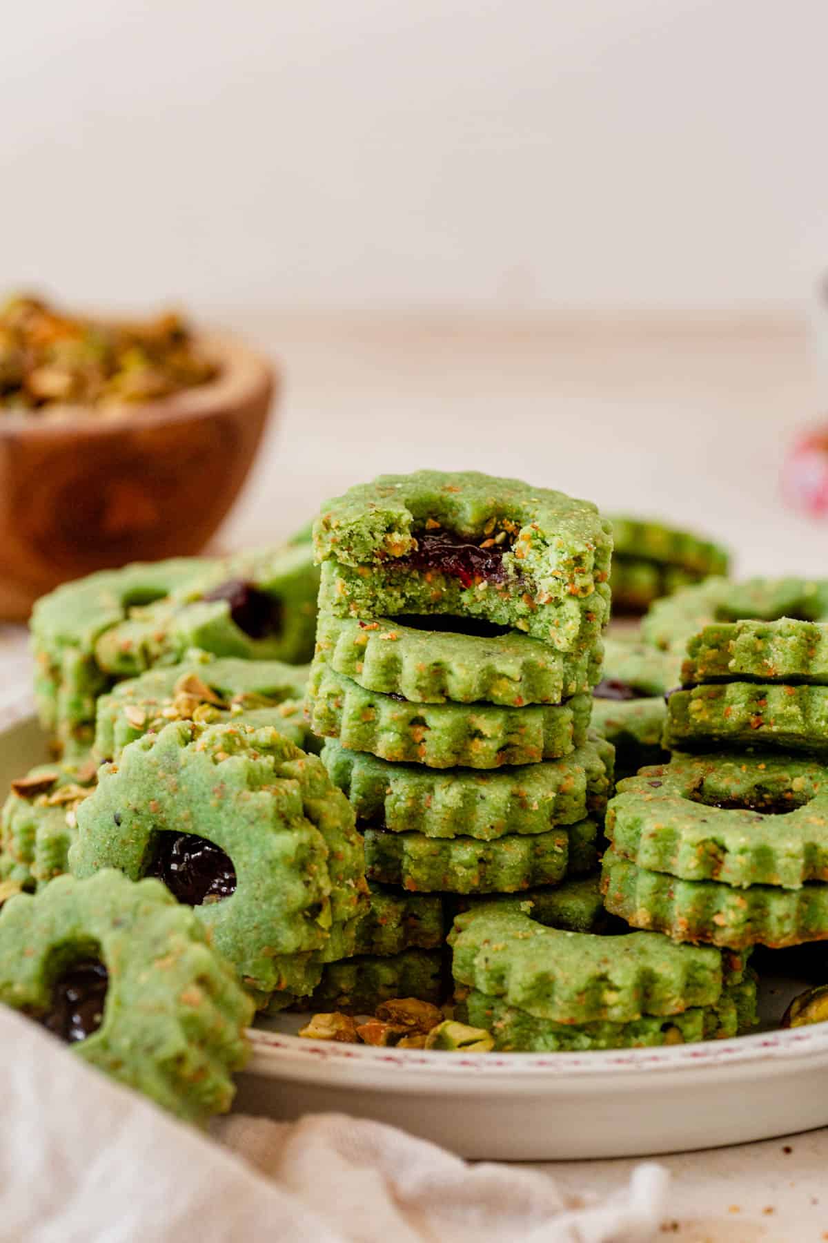 stacked pistachio linzer cookies on a christmas plate