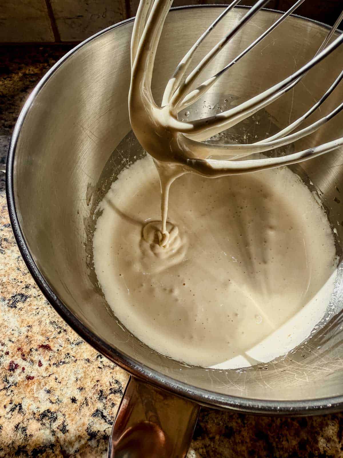 thick ‘ribbon-like’ trails of beaten sugars and eggs of the salted caramel brownie cookies coming off the whisk attachment of an electric stand mixer.