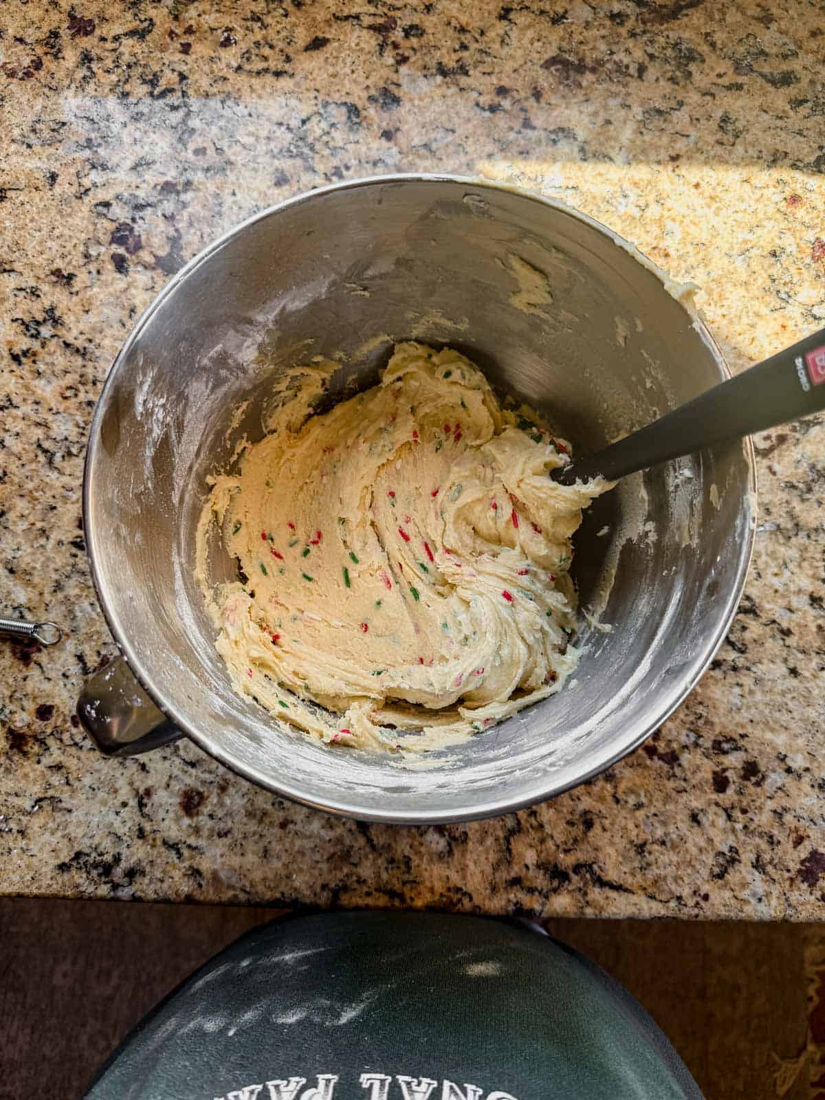 christmas sugar cookie dough with red and green sprinkles in a mixing bowl.