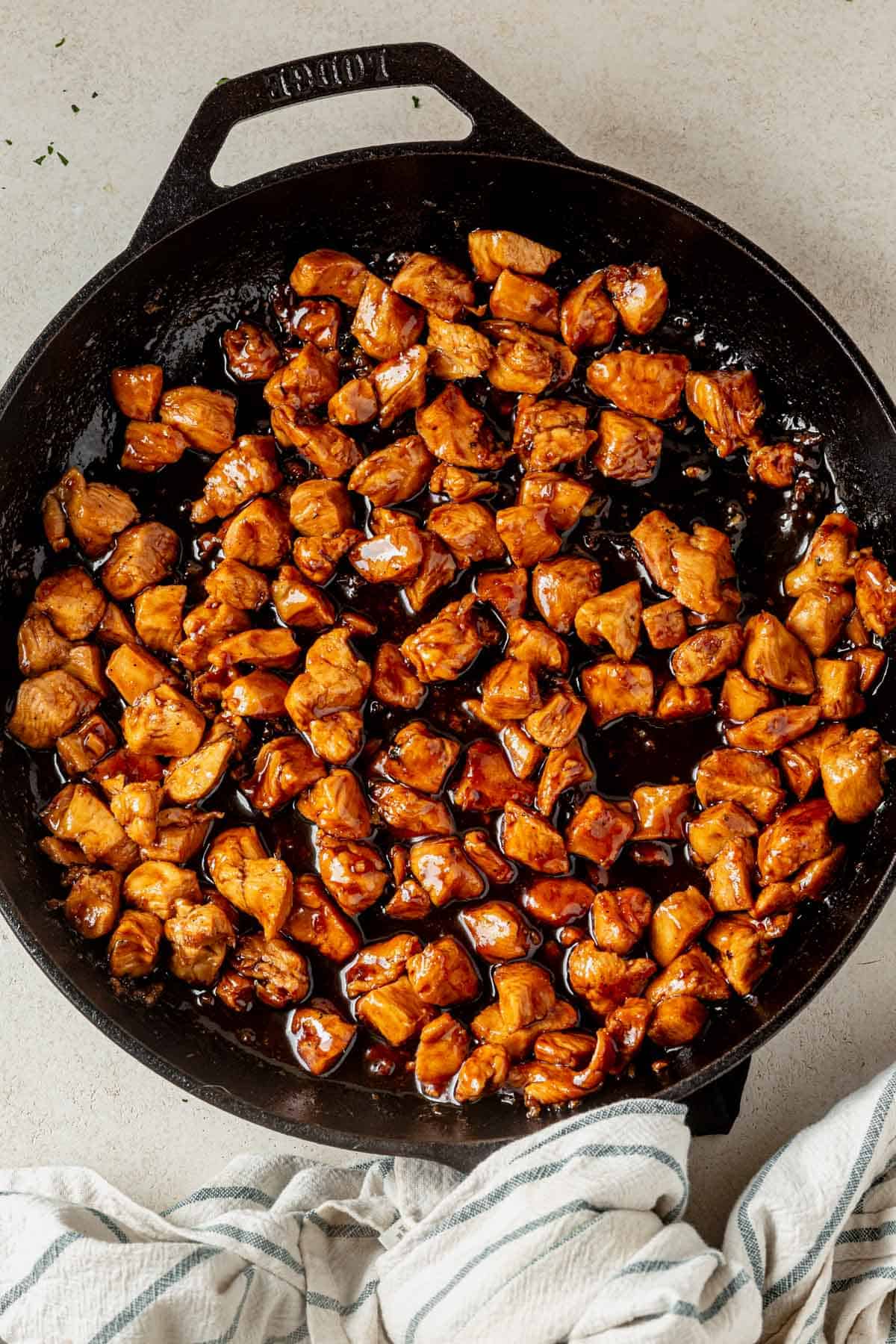 honey garlic chicken coated in a thick sweet sauce in a skillet.