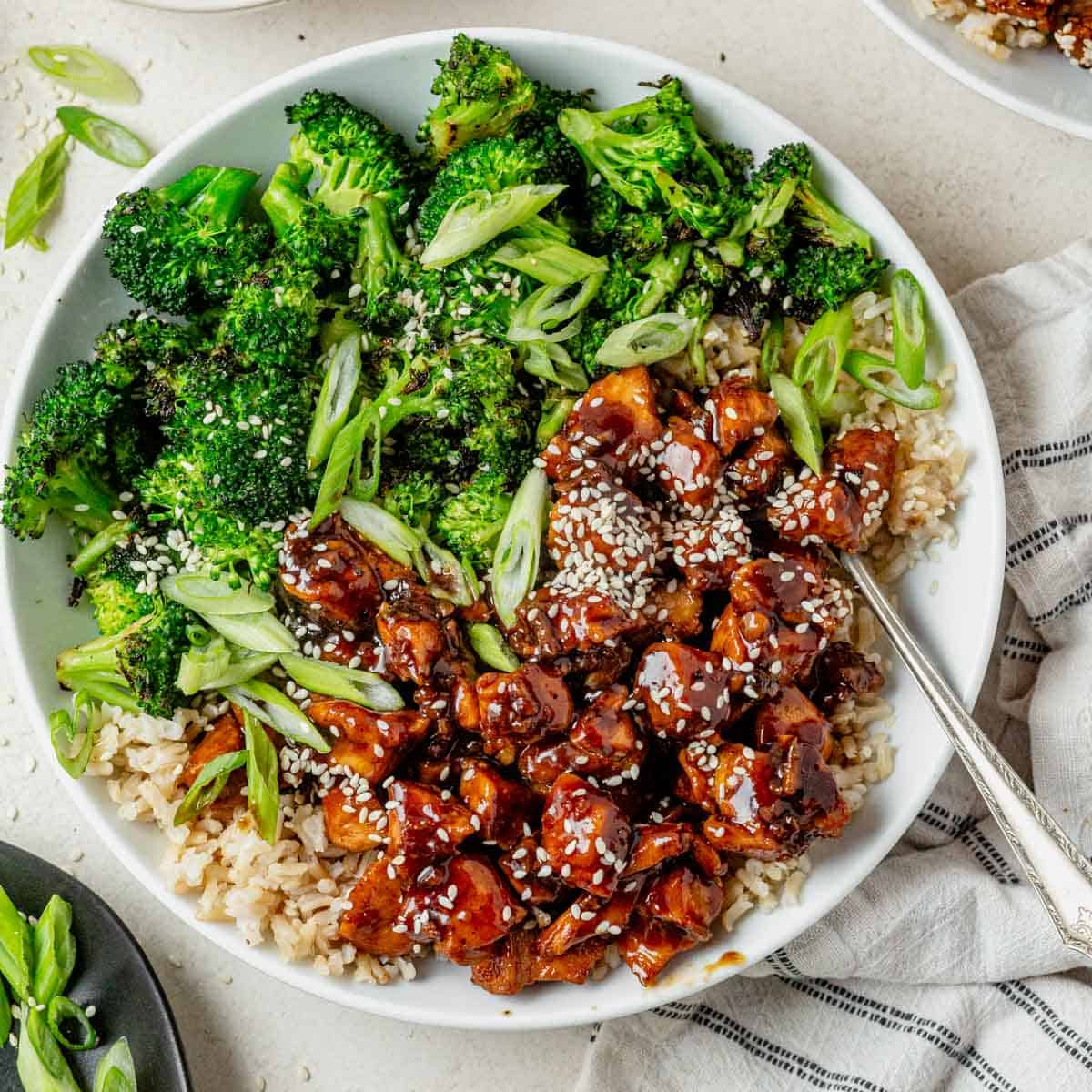 Honey garlic chicken meal prep bowl with sticky glazed chicken roasted broccoli rice and sesame green onion topping