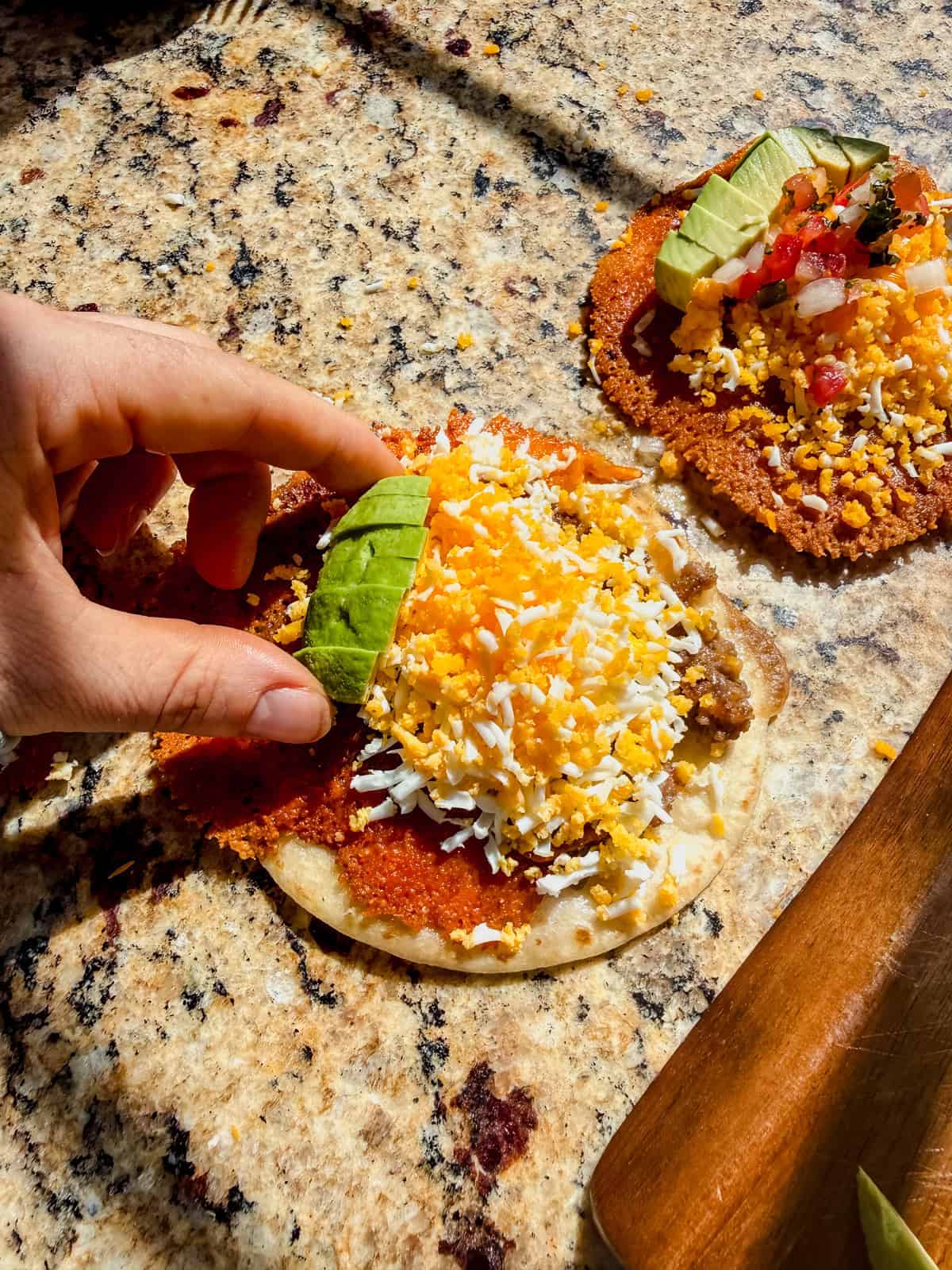 topping a crispy breakfast taco with avocado.