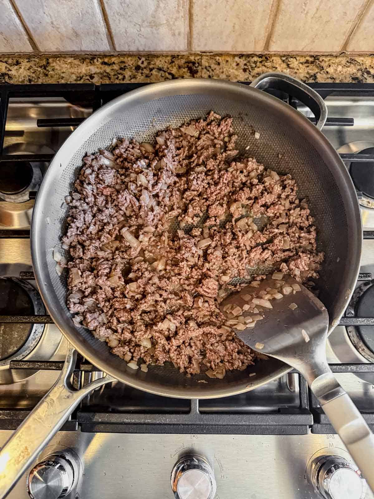 cooking onion, garlic, and ground beef in a skillet.