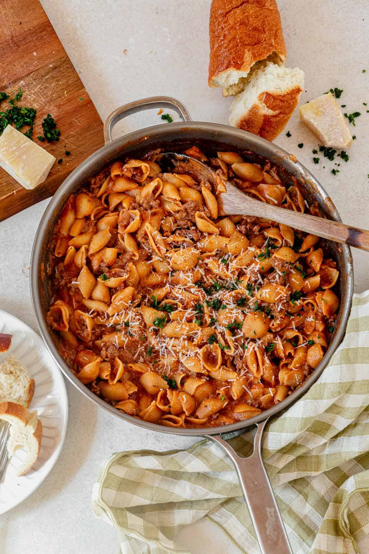 one pot creamy ground beef and shells in a skillet with crusty Italian bread next to it.