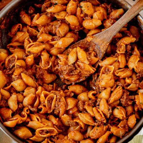 one pot creamy ground beef and shells in a skillet with a wooden spoon.