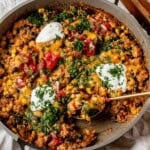 scooping a spoonful of ground turkey enchilada skillet out of the pan.