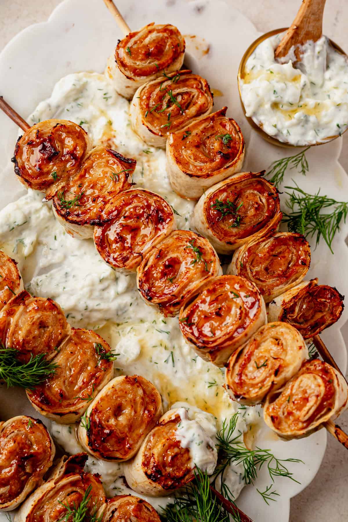 a lazy ground chicken kebab roll on a platter with a side of homemade tzatziki sauce.