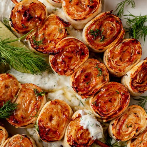 lazy kebab rolls on a platter with tzatziki sauce.