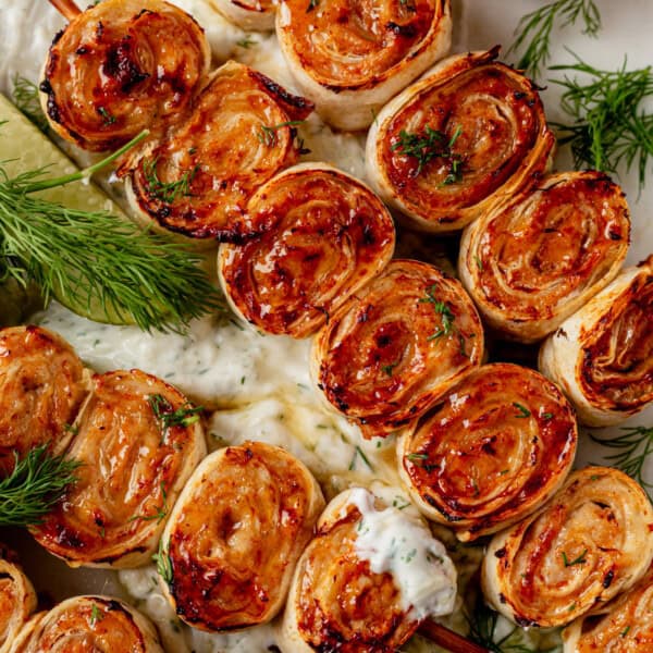 lazy kebab rolls on a platter with tzatziki sauce.