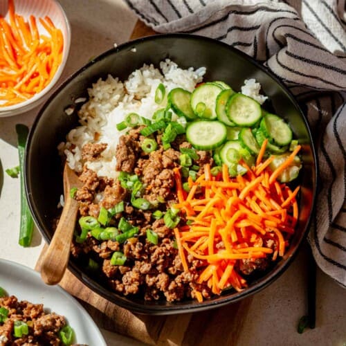 korean beef bowls with sticky rice and pickled carrots and cucumbers.