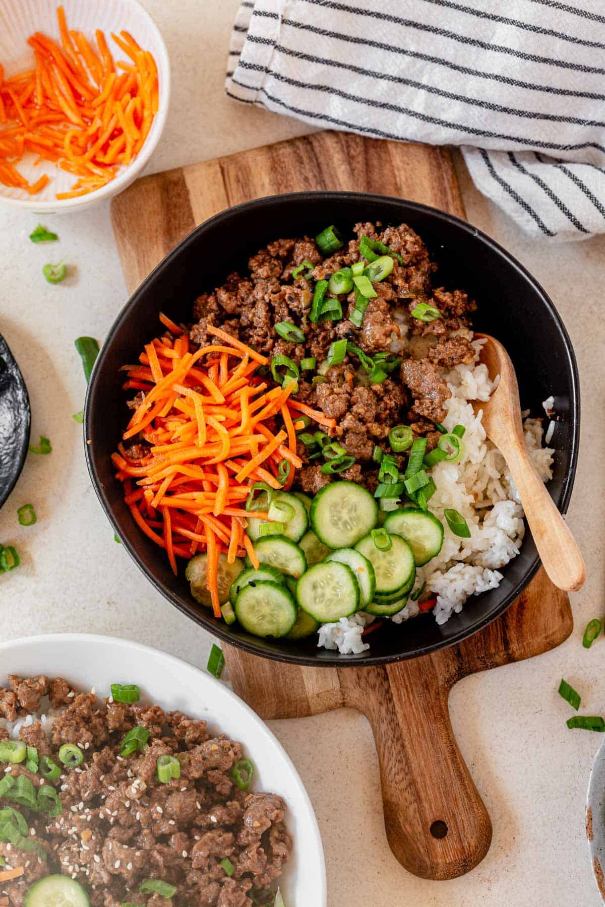 korean ground beef bowl on a cutting board with a wooden spoon.