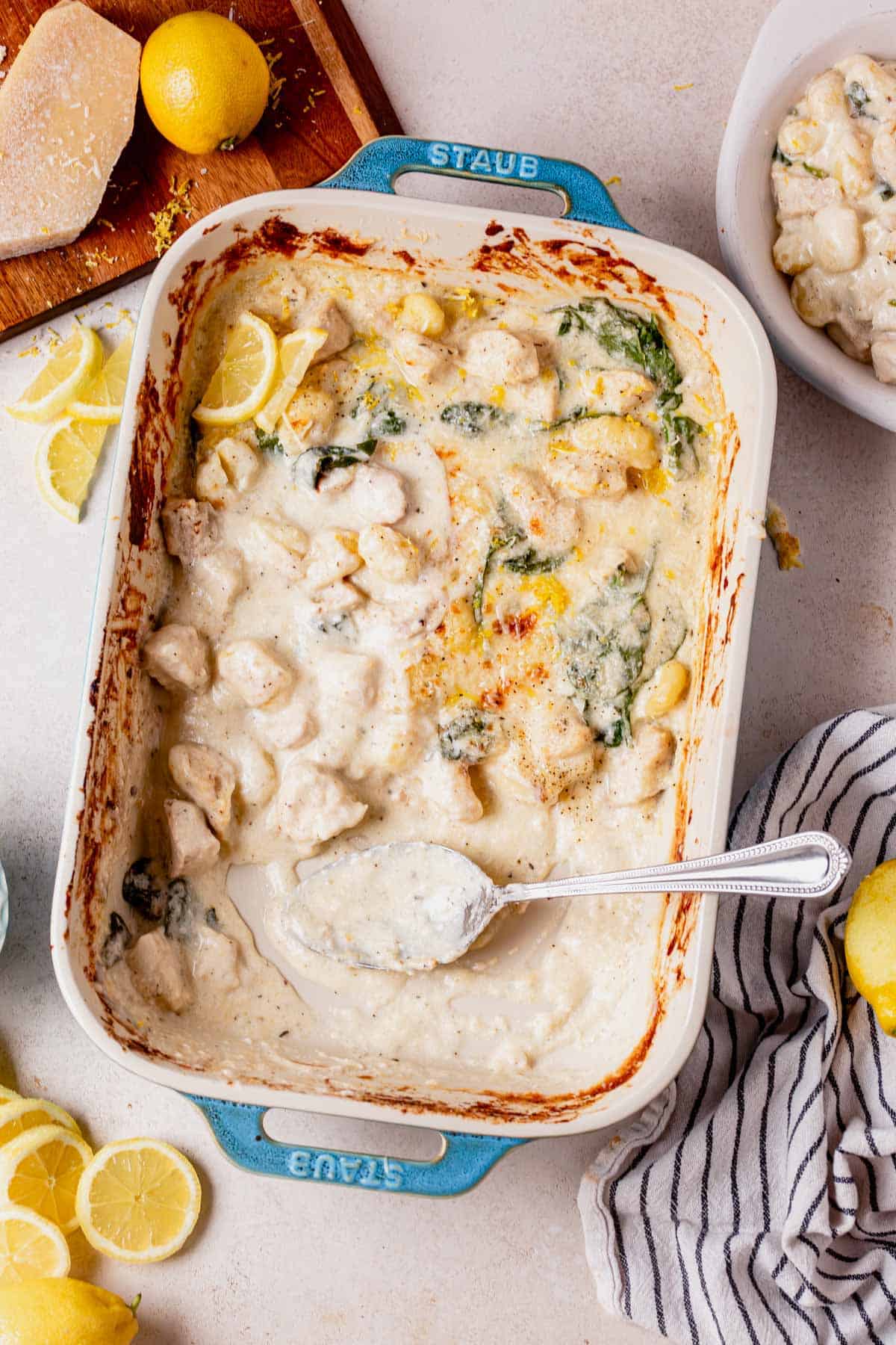 creamy lemon chicken gnocchi in a pan with some of it scooped out.