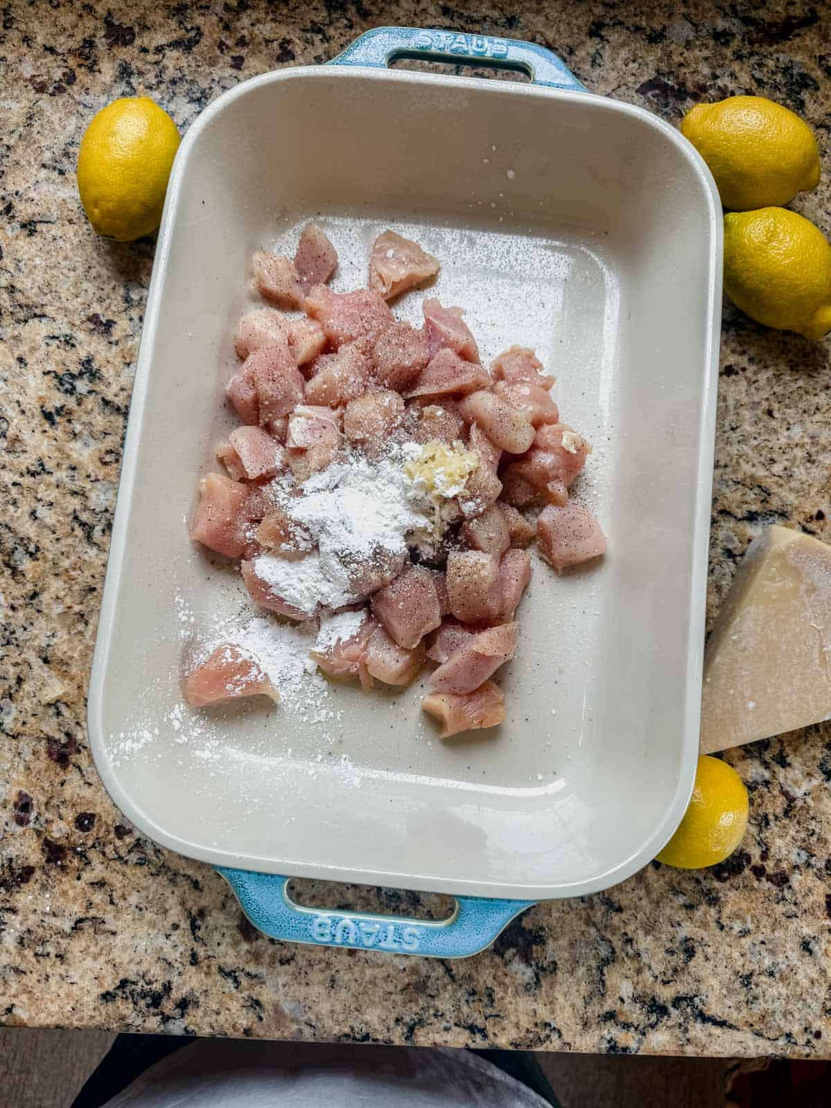 cubed chicken with spices and cornstarch in a casserole dish.