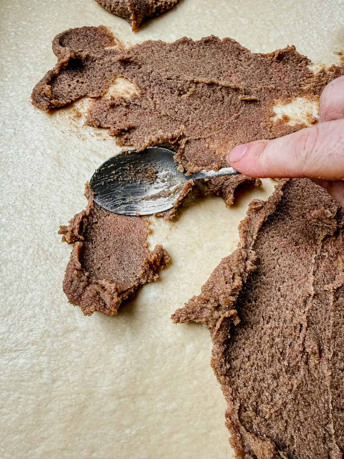 spreading cinnamon roll filling onto rolled out cinnamon roll dough.