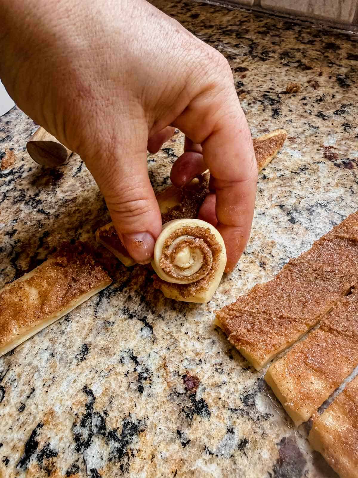 rolling a mini cinnamon roll.