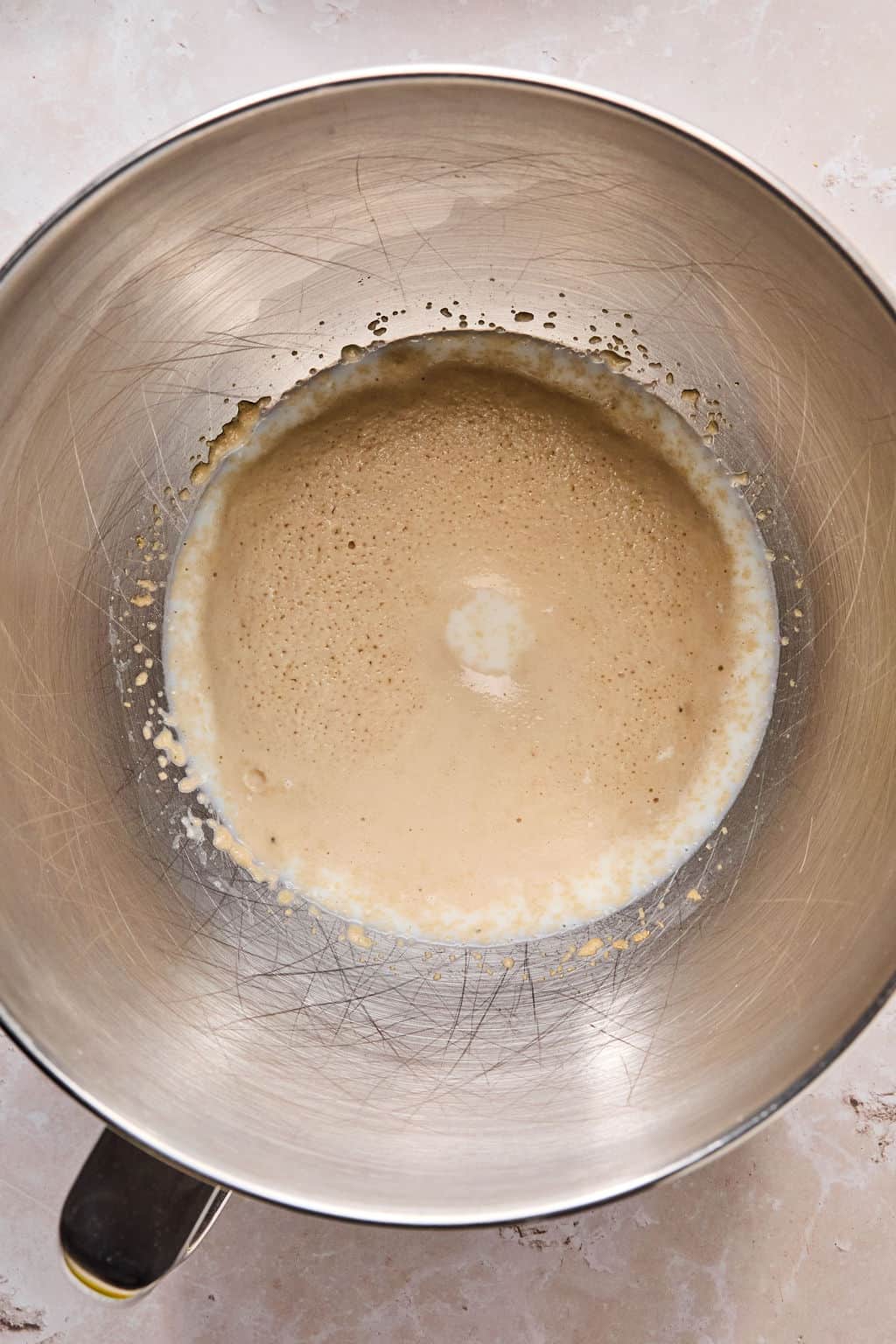 milk, yeast, and sugar whisked in a mixing bowl until its activated and frothy.