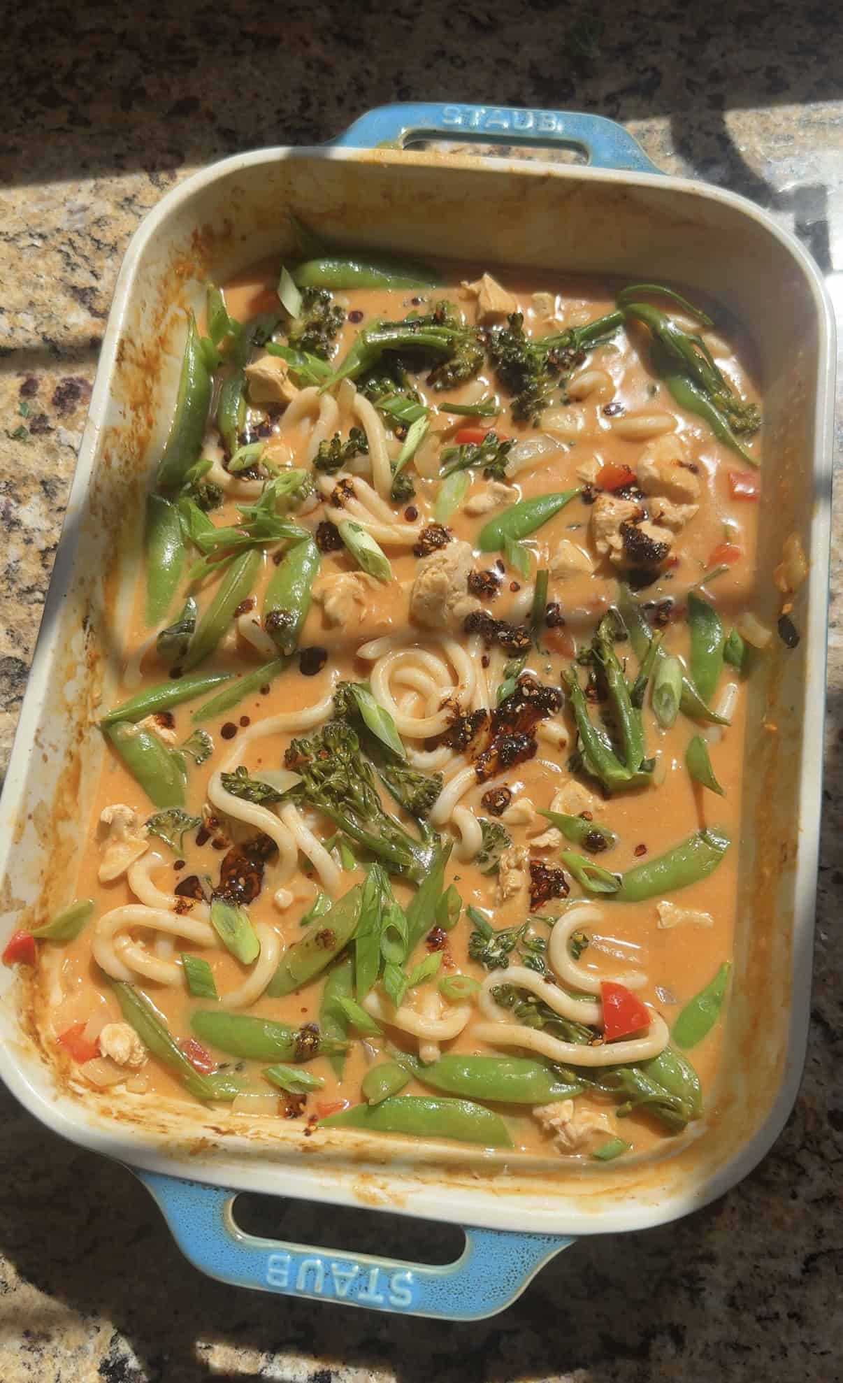 topping baked chicken curry noodles with green onion and cilantro.