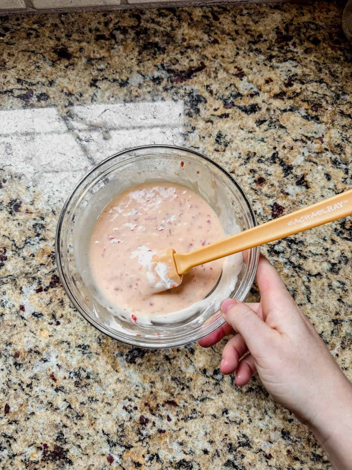 mixing bang bang sauce in a glass bowl on the counter.
