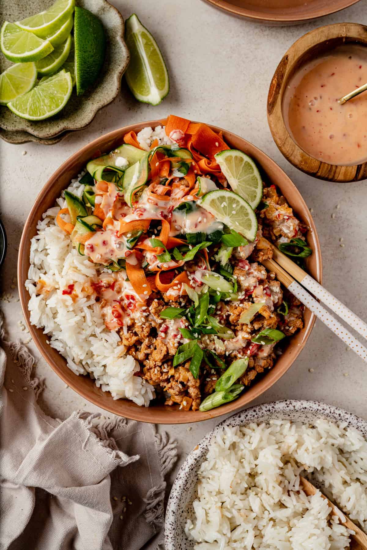 a bang bang turkey rice bowl next to a bowl of coconut rice and lime wedges.