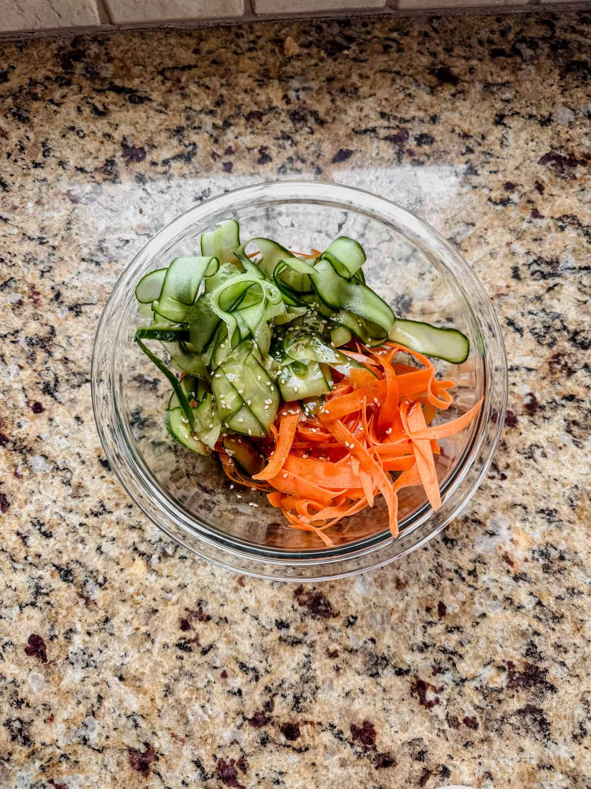 cucumber carrot salad mixed in a glass bowl.