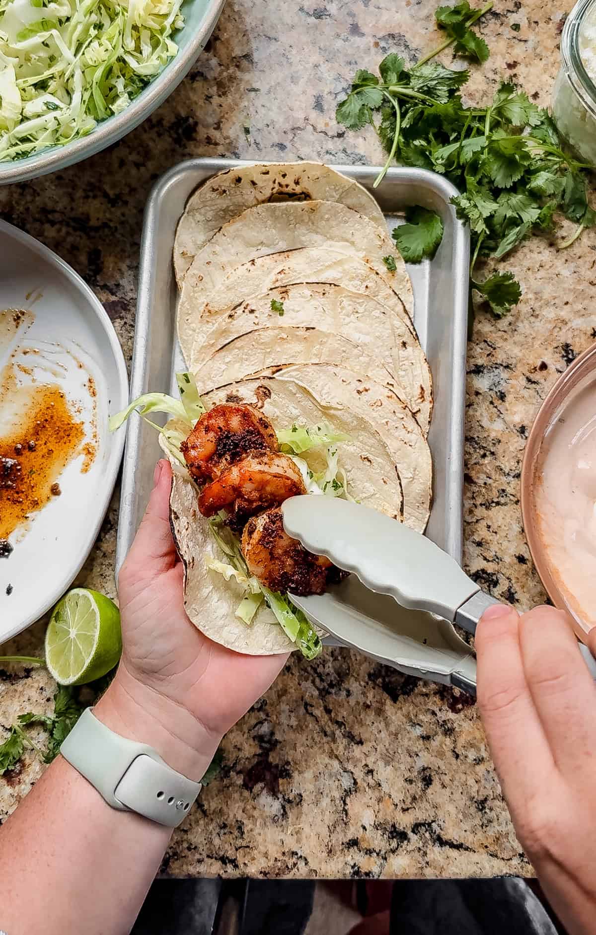 adding blackened shrimp to a taco with cilantro slaw.