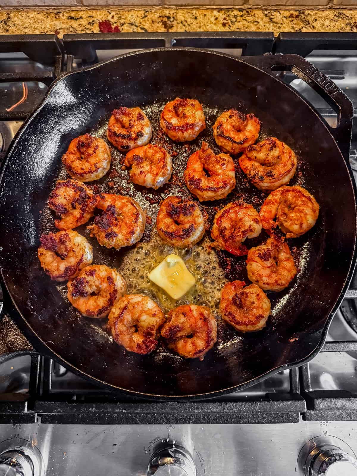 blackened shrimp cooked in a cast iron skillet with melted butter.