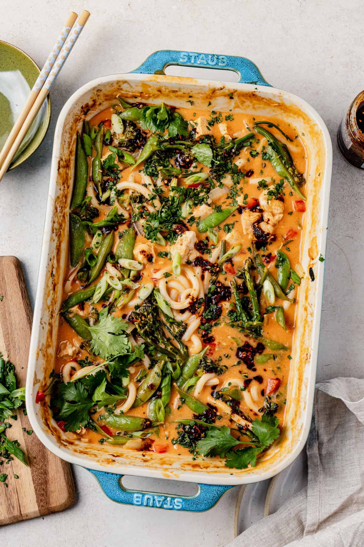 baked chicken curry noodles on a counter with fresh cilantro and green onions on top.