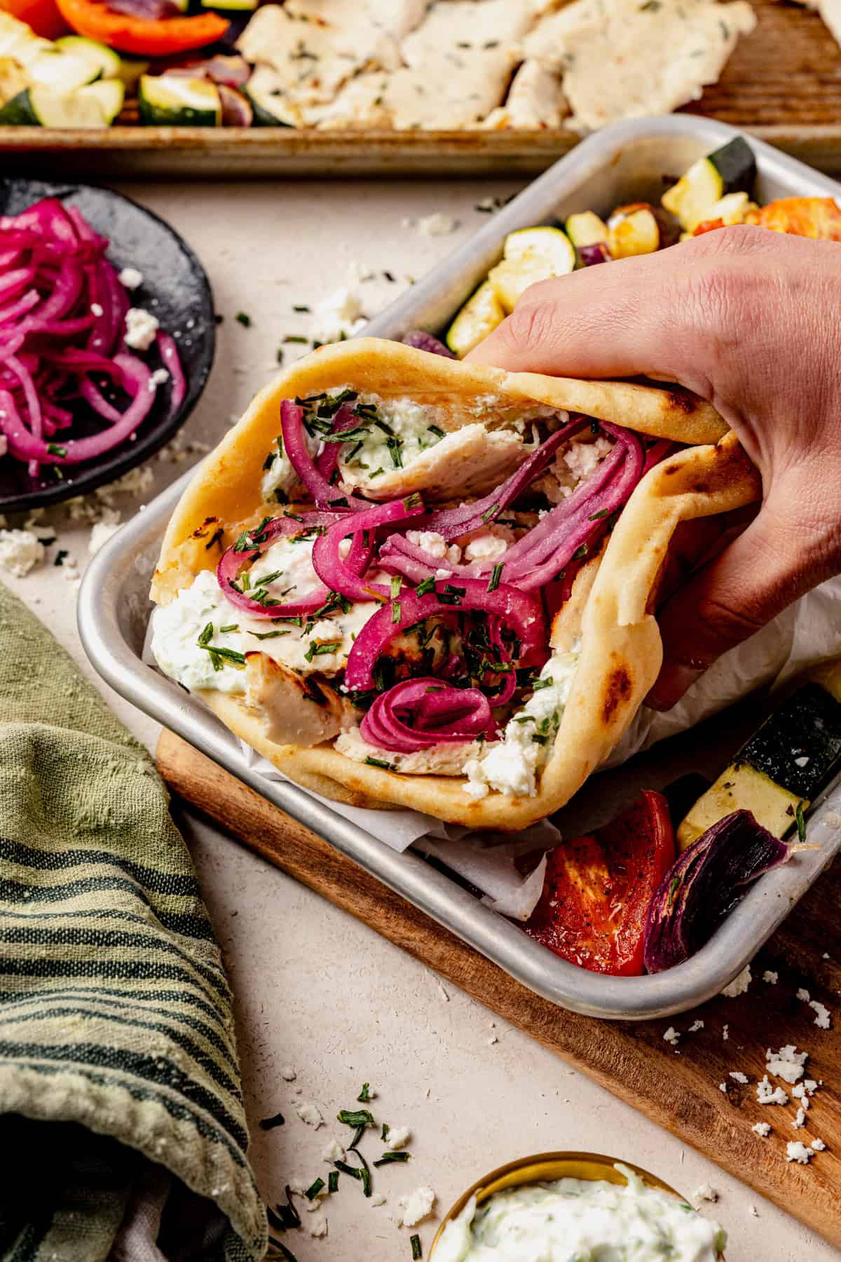 a chicken doner kebab on a serving plate with feta, pickled onion and fresh herbs in a pita.