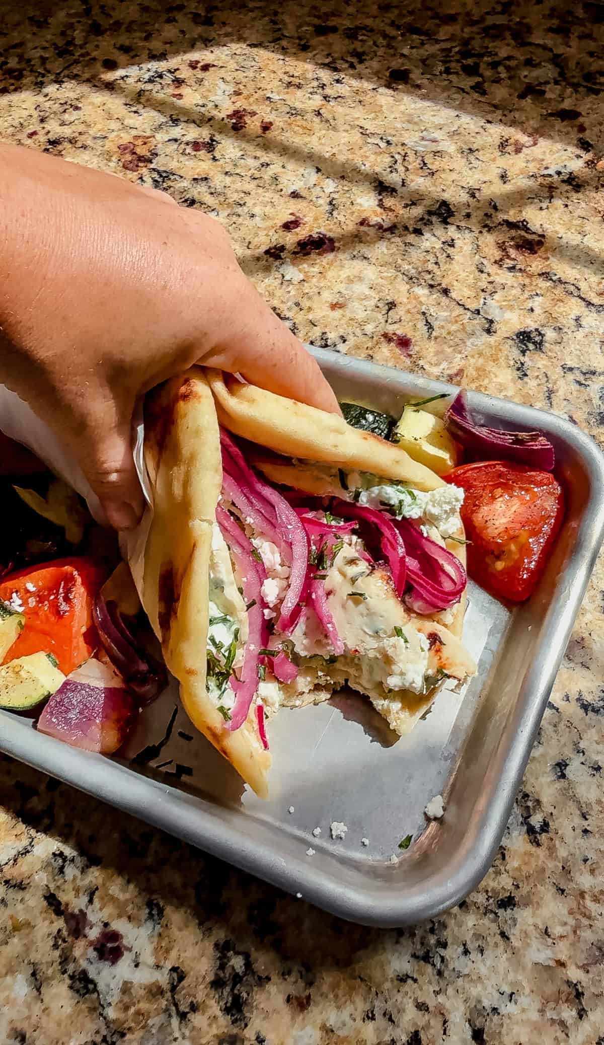a bite taken out of a chicken doner kebab on a serving tray.