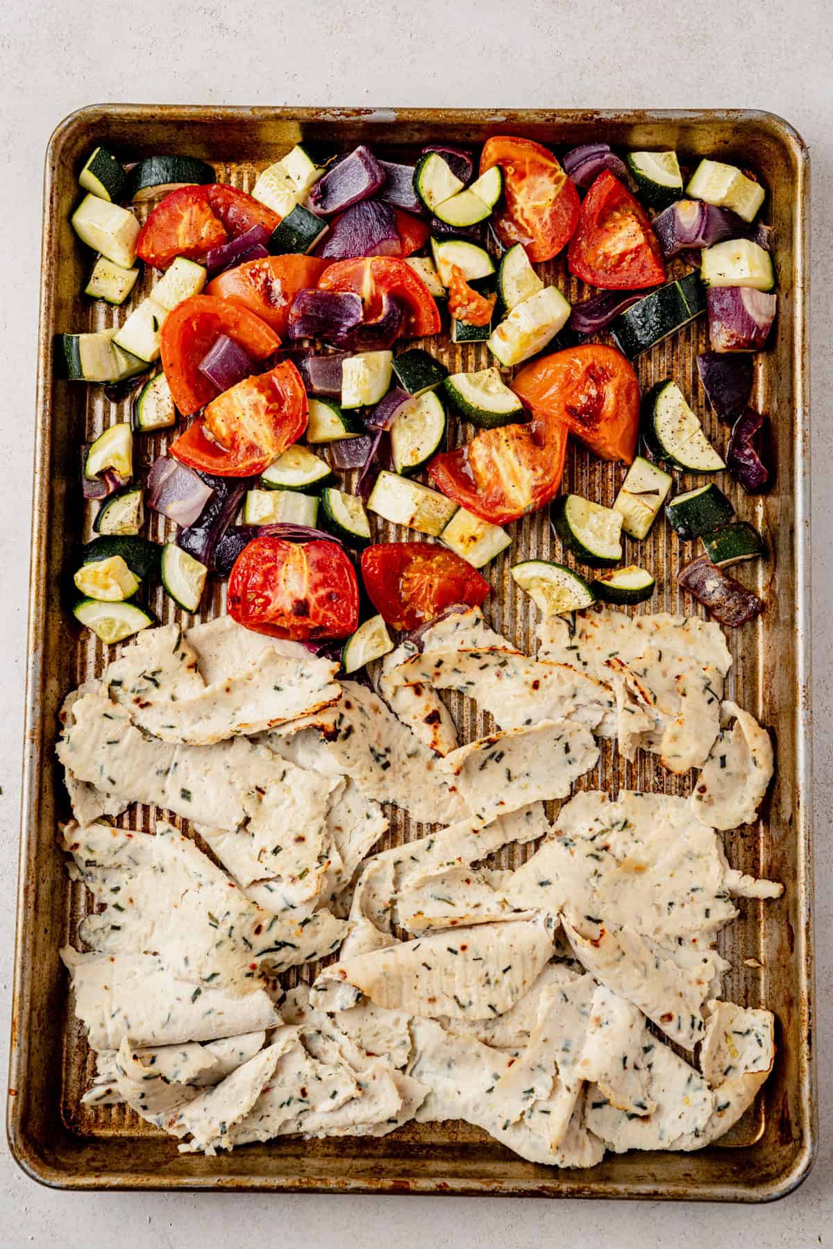 chicken doner strips on a sheet pan with roasted vegetables.