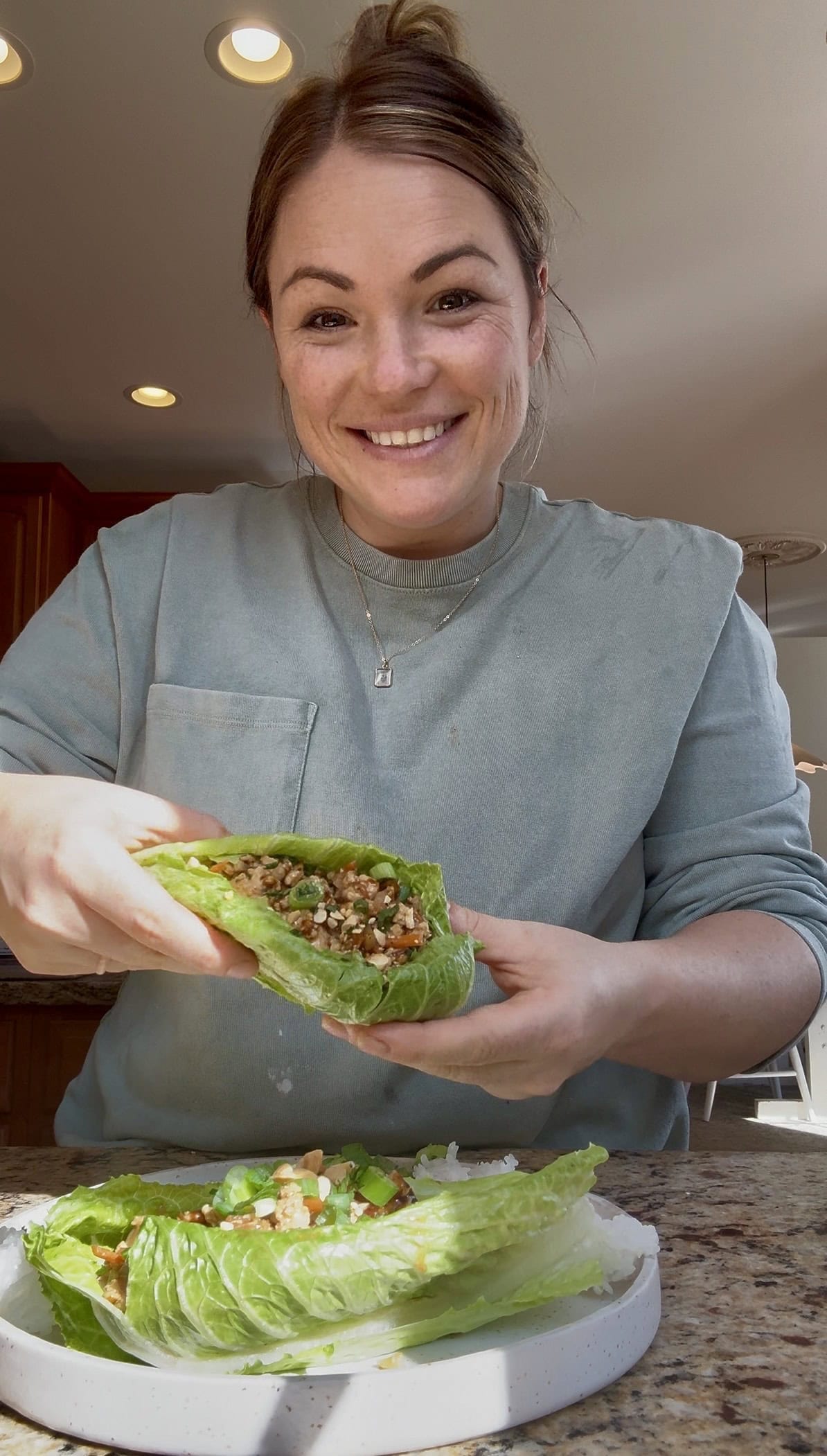 molly holding a ground chicken lettuce wrap at the counter.