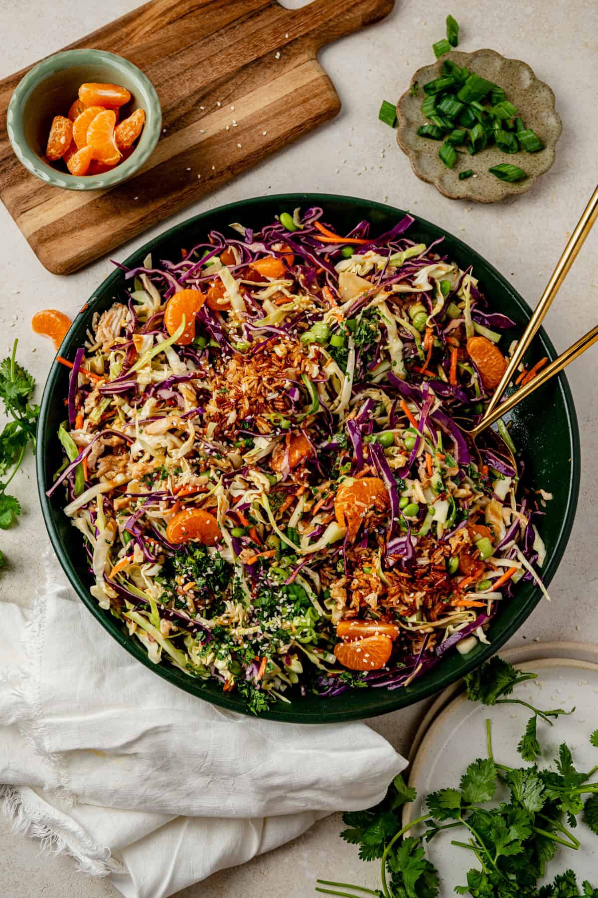 mandarin orange chicken salad in a large serving bowl with gold serving utensils resting in it.