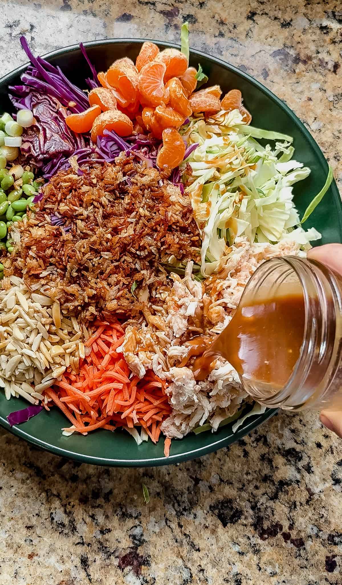 pouring dressing on top of mandarin orange chicken salad.
